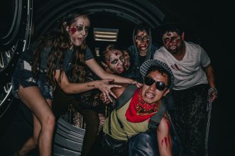 Group of people in zombie makeup, embracing a Halloween theme at night in Ciudad de México.
