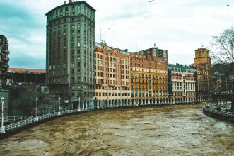 Vibrant architecture along the Nervión River in Bilbao, Spain on an overcast day.