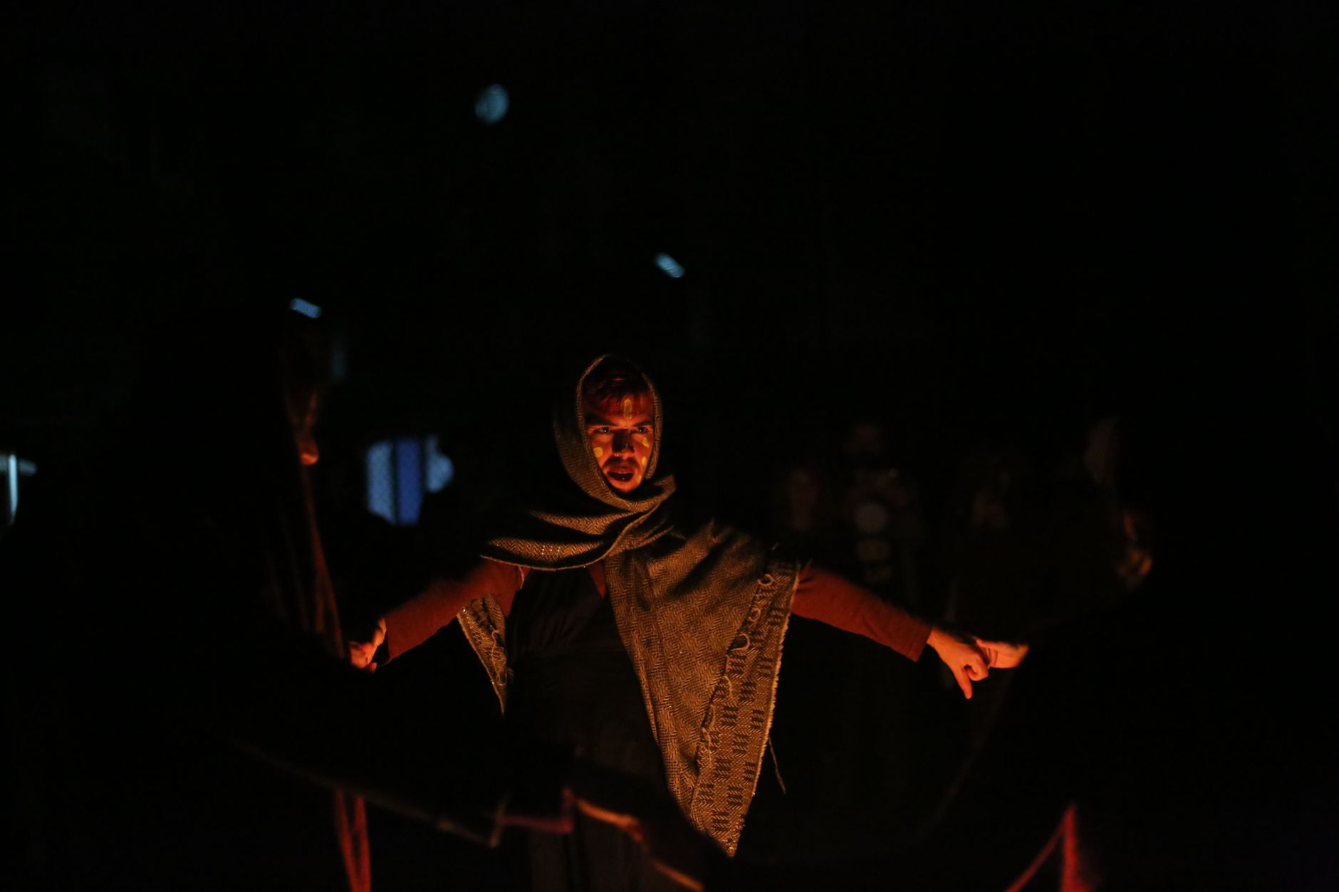 A nighttime dance ritual with people holding hands in Italy, shrouded in darkness and mystery, invokes cultural intrigue.