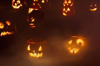 Creepy jack-o'-lanterns glowing in thick fog, creating an eerie Halloween night ambiance.