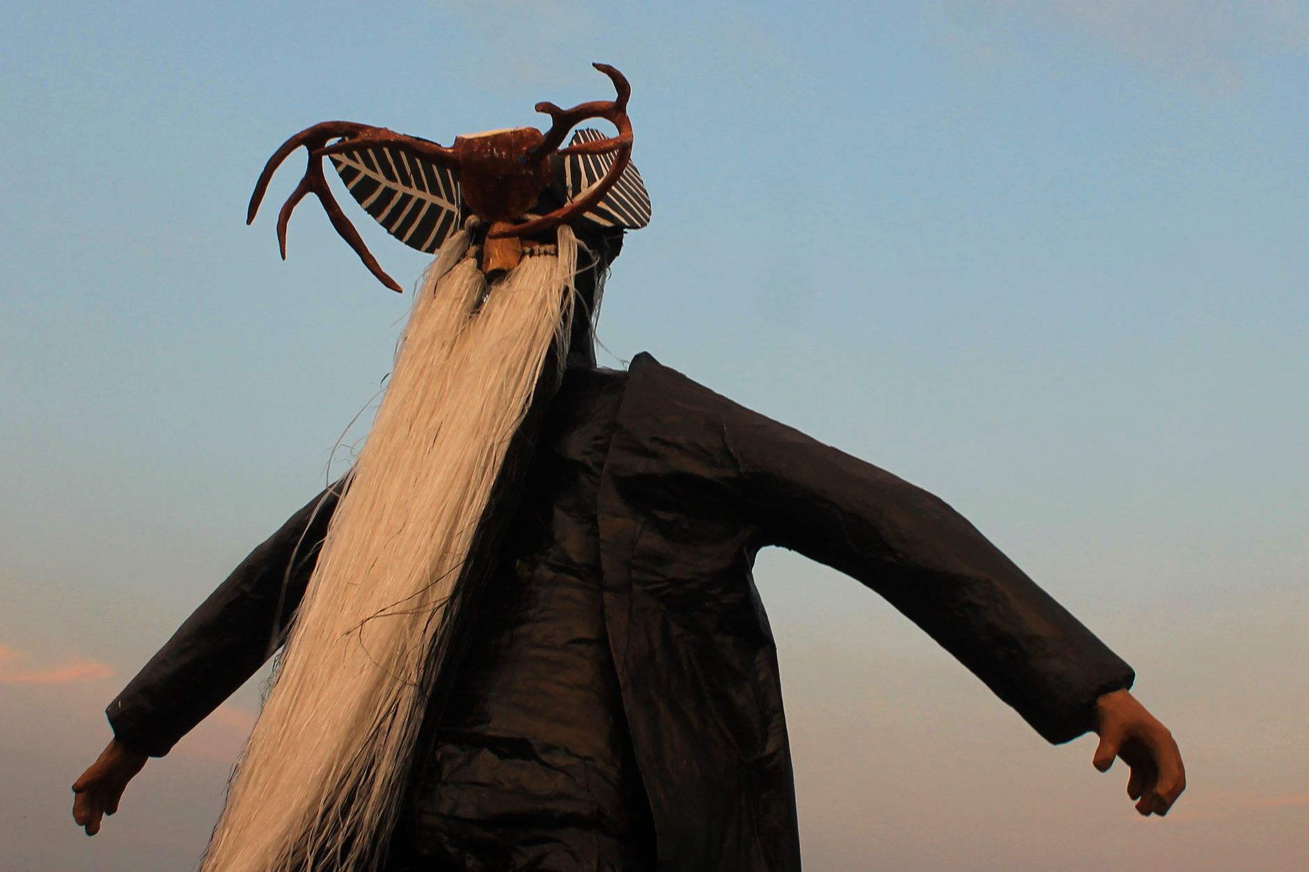 Back view of Mexican cultural effigy with unique headdress against clear sky, Acapulco.