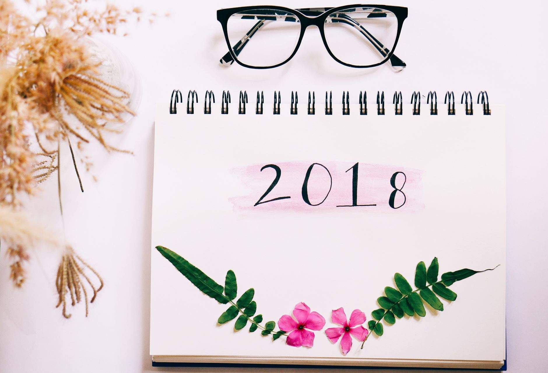 An artistic 2018 calendar with floral embellishments and eyeglasses, perfect for New Year decor.