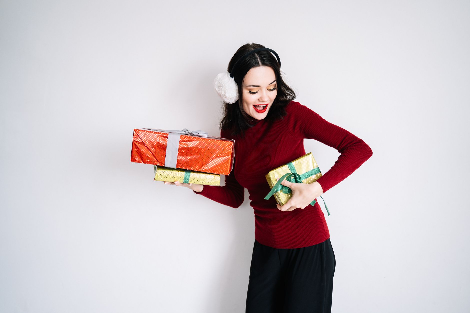 Caucasian woman joyfully holding wrapped holiday presents, celebrating Christmas.