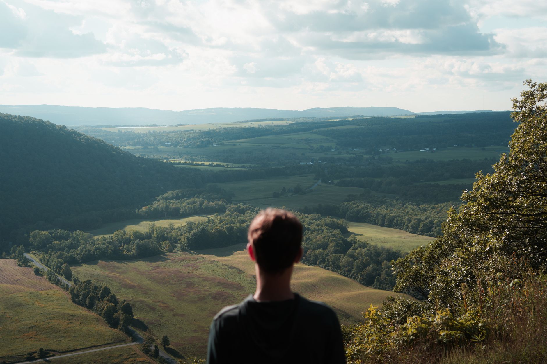 A person enjoys the picturesque view from Jones Hill overlooking Tully, NY, in summer.