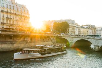 A scenic view of a river cruise boat on the Seine during sunset in Paris.