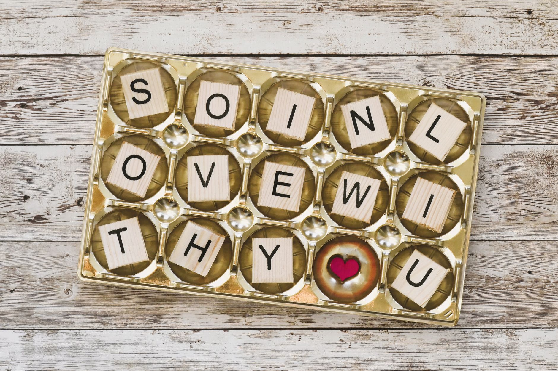 Romantic message spelled with wooden blocks in a box, symbolizing love and affection.